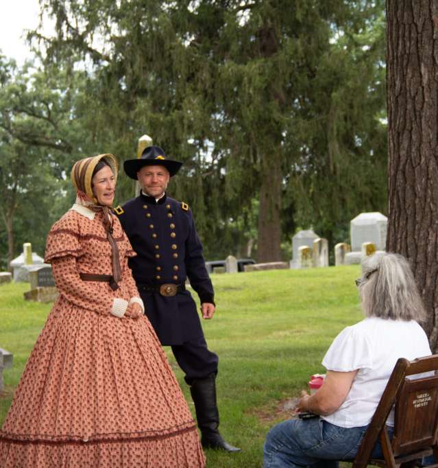 Couple dressed in period style clothing, performing in a cemetery walk.