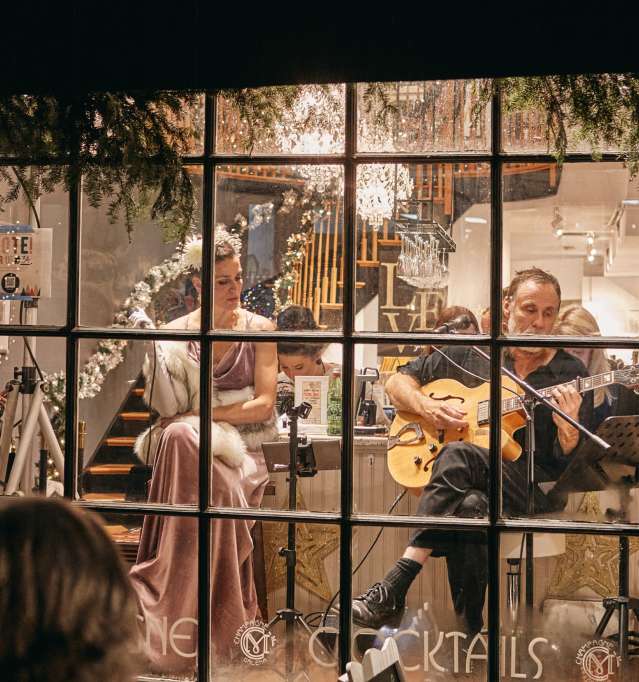 A holiday shop window display with people looking inside, from the outside.