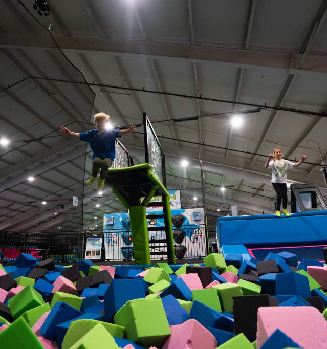 Two kids jumping into ball pit at Sky's the Limit