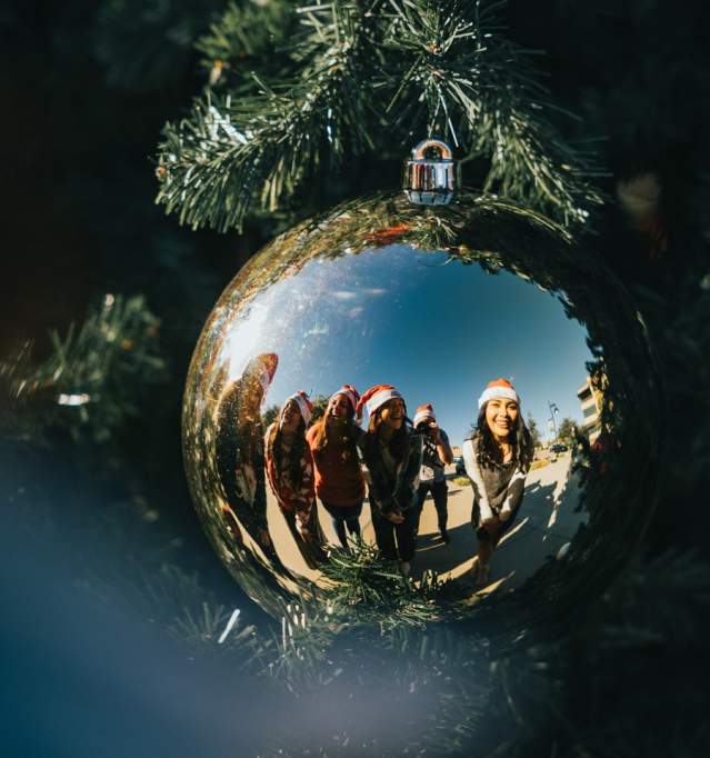 People smiling into a christmas ornament on the city of temple tree
