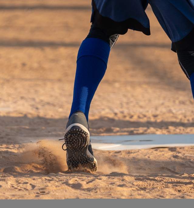 softball cleats on the batting mound as the pitcher swings