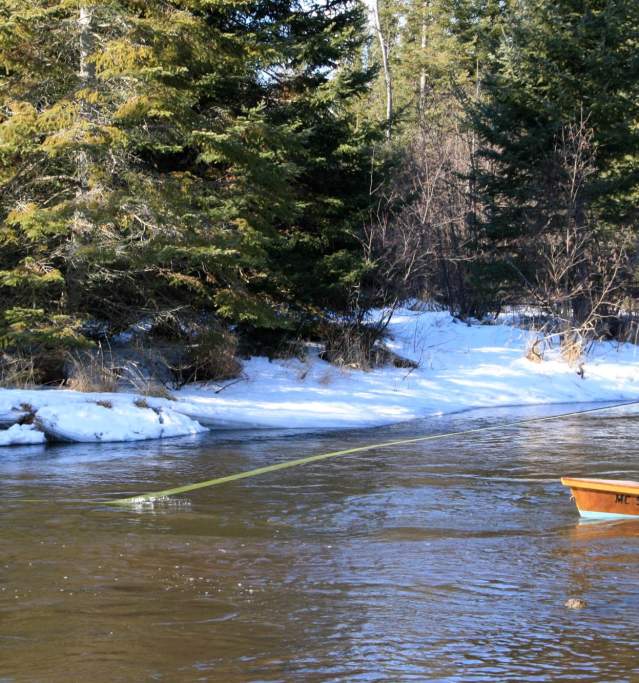 man standing in boat fishing in river