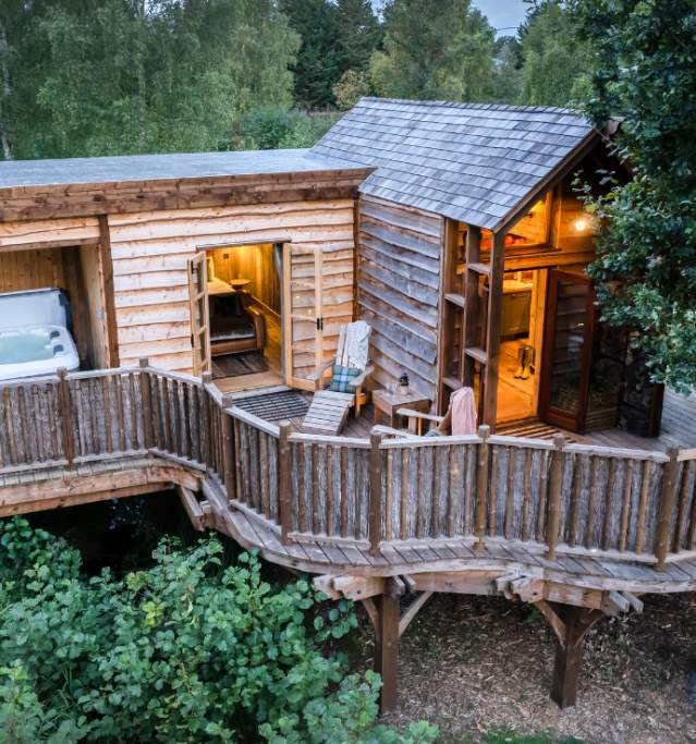 Exterior of a lodge in the woods with hottub