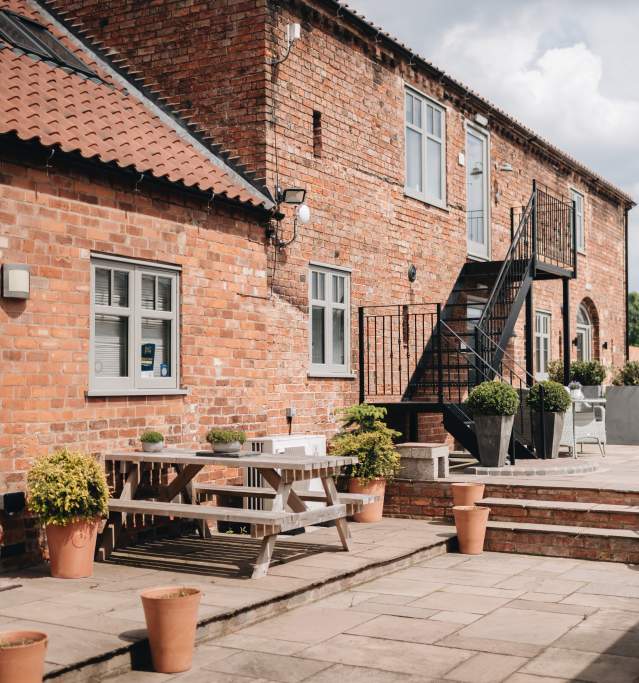 Accommodation exterior with picnic benches and plants