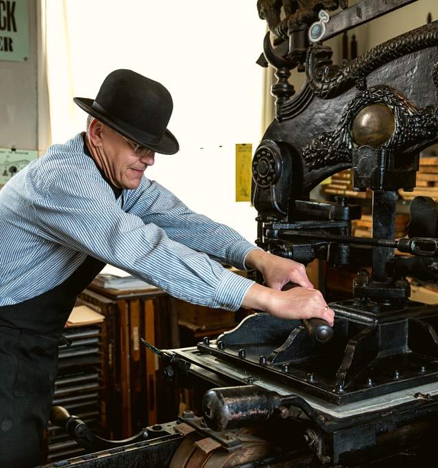 A man using a vintage printing press in the Museum of Lincolnshire Life