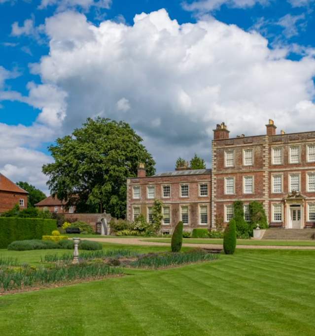 A historic house with grass in foreground and blue skies