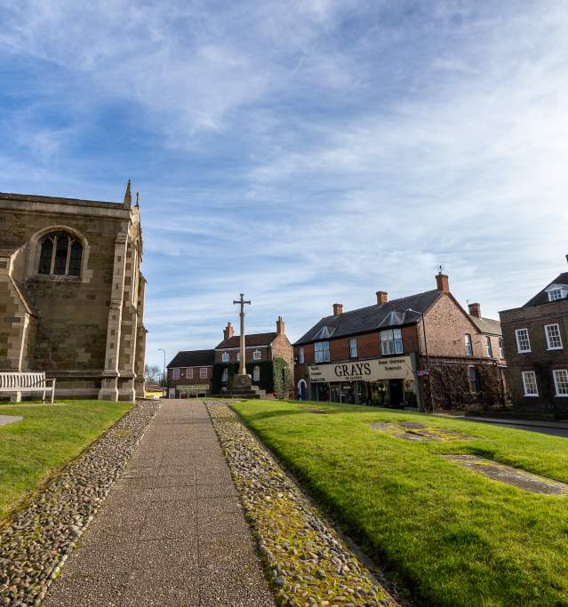 A church to the left and houses to the right under blue skies