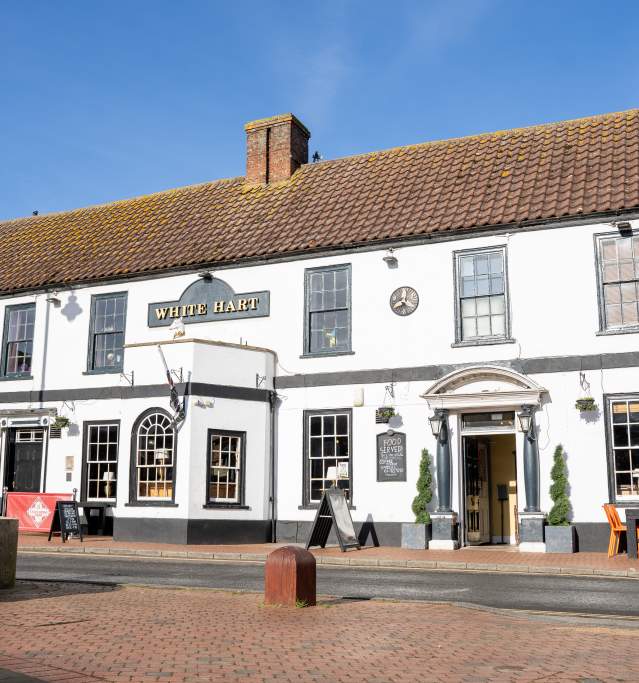 outside of a white pub under blue skies with outdoor seating