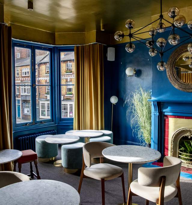 A hotel lounge with blue walls and marble tables with chairs