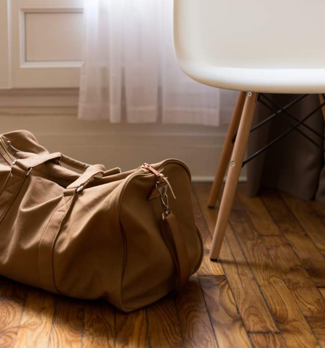 Brown duffle bag on floor next to white chair