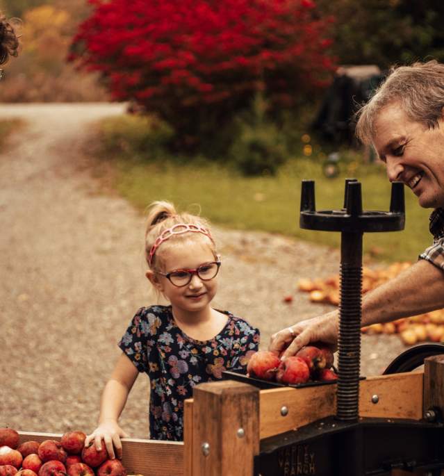 Two children and man mashing apples into juice
