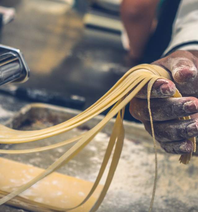 Hand pulling homemade pasta through pasta maker
