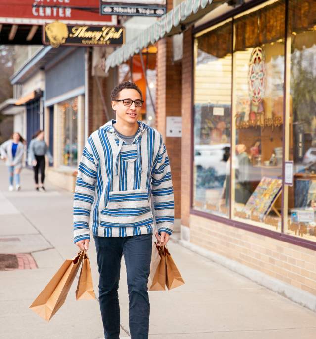 Man walking down street with shopping bags outside storefronts