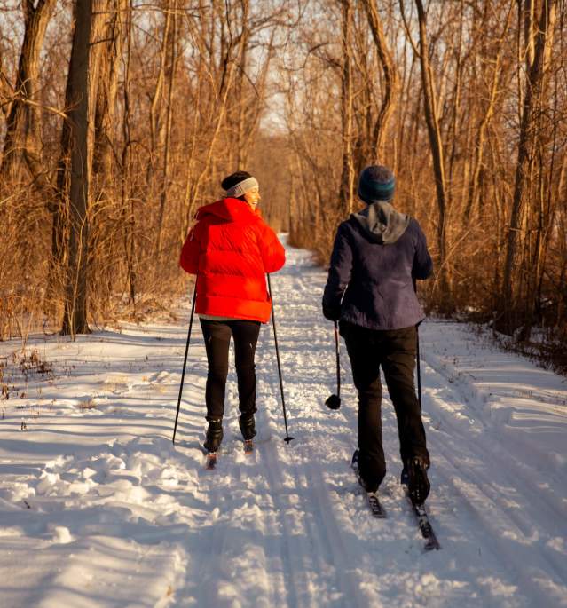 Two women cross country skiing down snowy trail