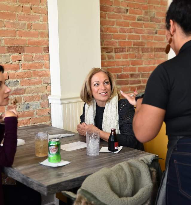 Two women ordering from worker at restaurant