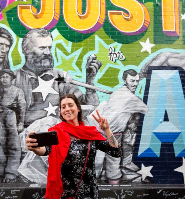 Woman taking selfie in front of colorful mural