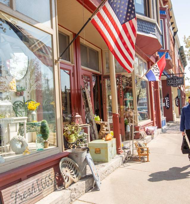 Woman walking down sidewalk past storefronts