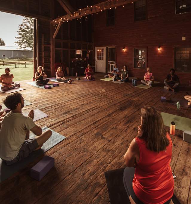 People doing yoga in circle inside barn