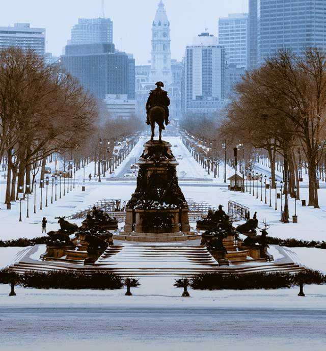 Statue facing Benjamin Franklin Parkway and City Hall in Philadelphia covered in snow
