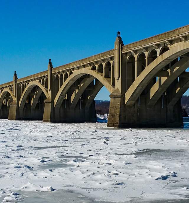 A frozen river with an arched bridge on a sunny day