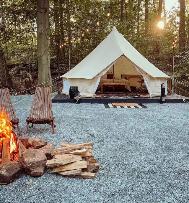 A glamping tent with a lit fire and chairs in front