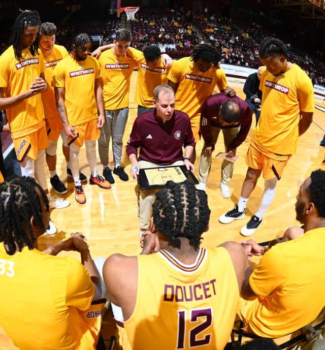 University basketball players in a circle around their coach with a play sheet