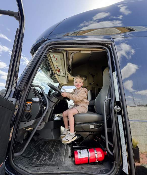 Image of boy sitting in the driver seat of an 18 wheeler.
