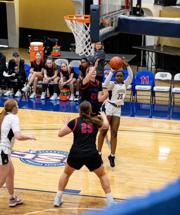 Image of girl shooting a basket over an opponent in the Holiday Classic tournament.