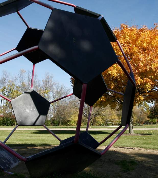 Giant metal soccer bar art installation in a fall colored park.