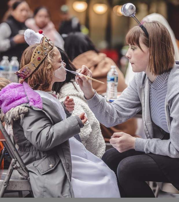 Child getting their face painted by a woman at Boo + Brew in Bridge Park