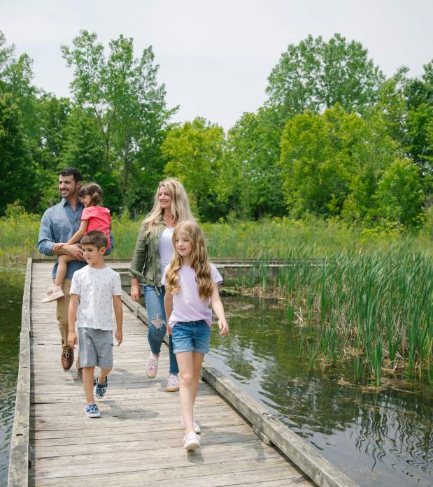 Family of five walking a boardwalk over a marsh at the M.L. Red Trabue Nature Preserve