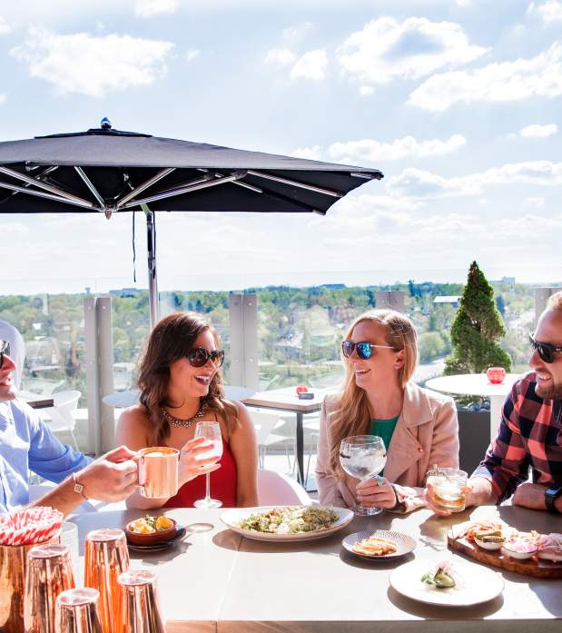 A group of friends enjoying cocktails and appetizers on the rooftop patio at VASO on a sunny day.