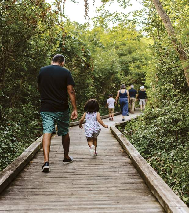 A family running down the boardwalk at Kiwanis Riverway Park