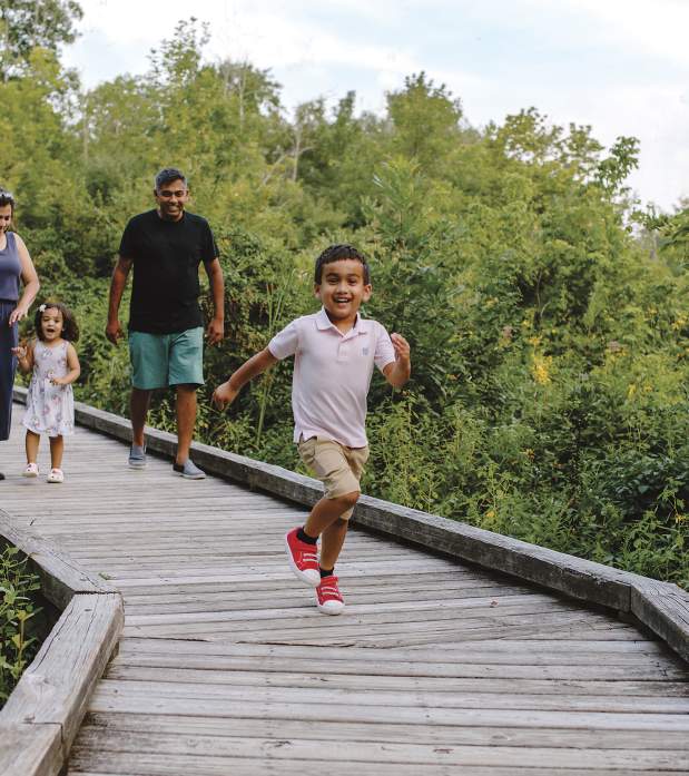 Kid running in front of his family on the boardwalk at Kiwanis Riverway Park