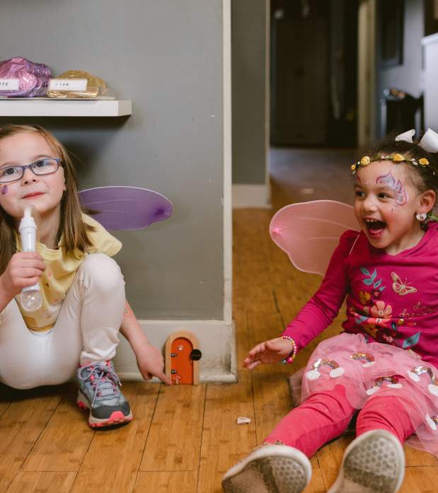 Two little girls dressed in fairy wings finding the fairy door in Winans on the Fairy Door Trail