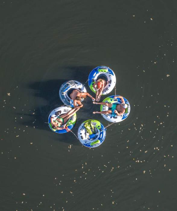 The overview of five tubes with adults sitting in them on a lake