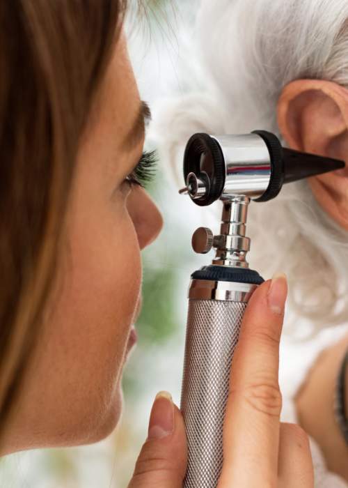 doctor looking in lady's ears with otoscope