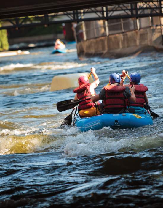 A group of people rafter down the East Race Waterway in the heart of downtown South Bend