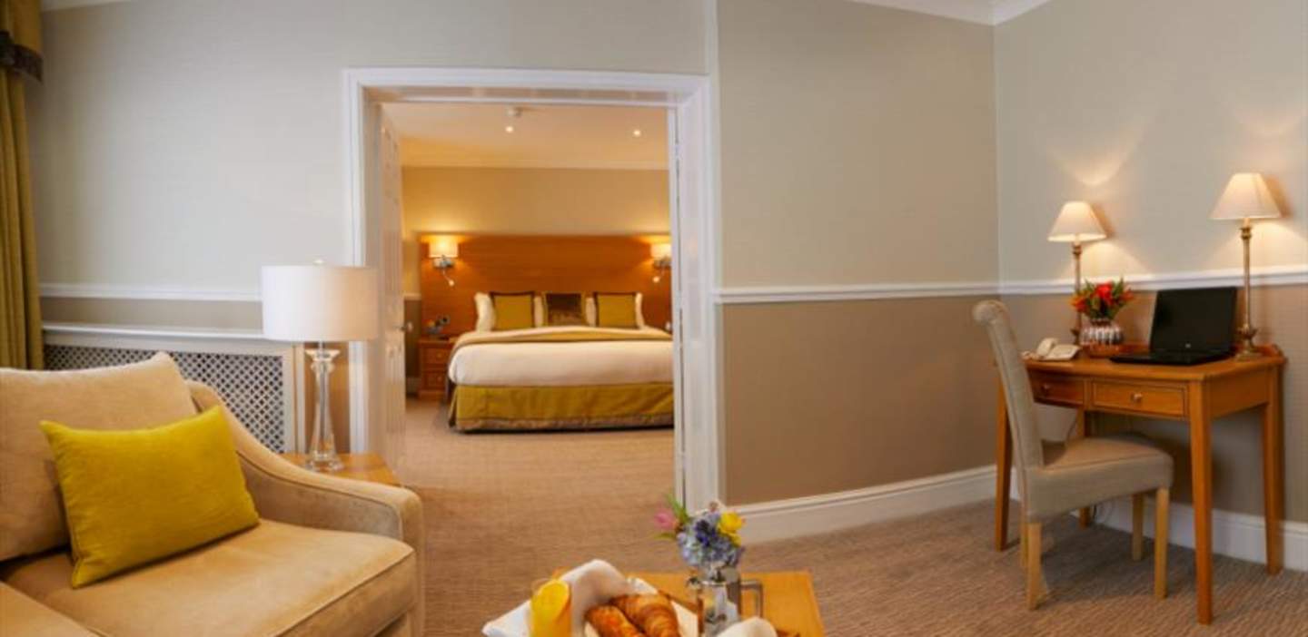 A clean, inviting hotel room with a basket of breakfast food on the table