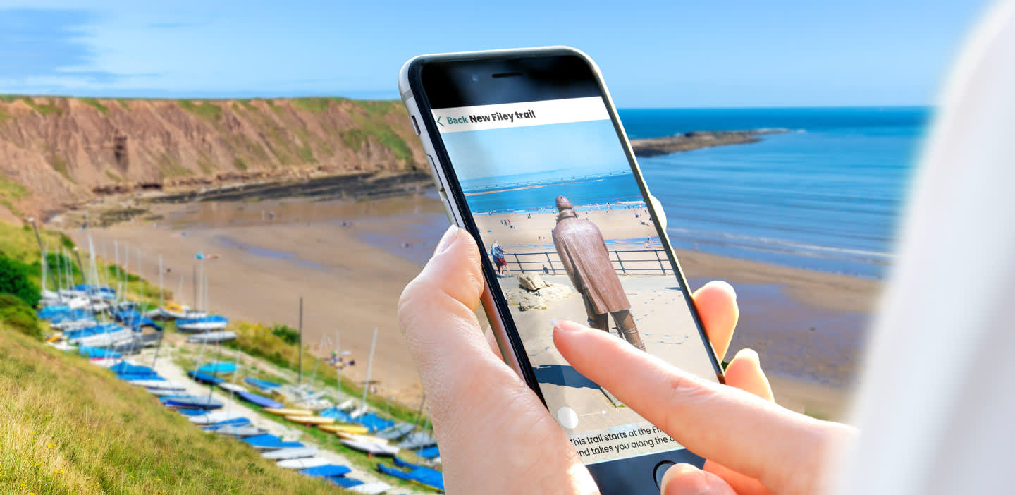 Someone on the Filey coast using their phone to explore secrets and history