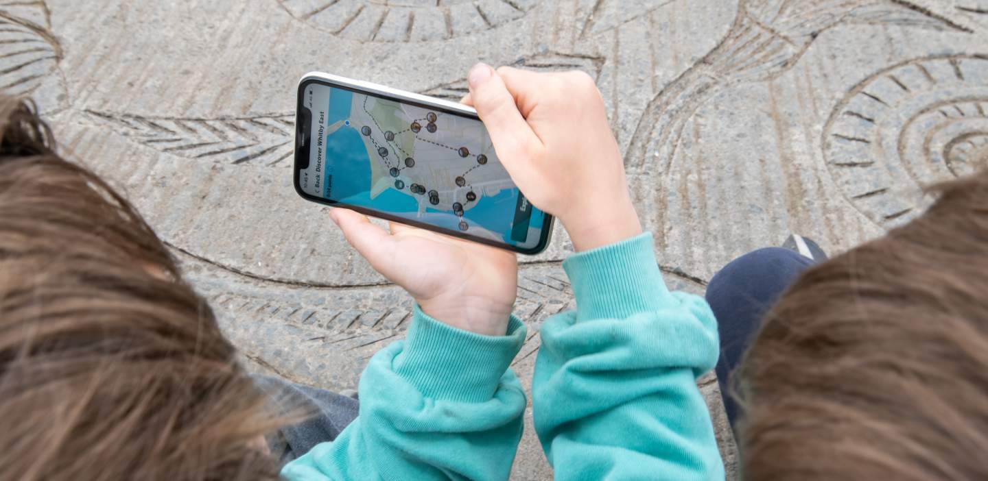 Two young people enjoying an AR app on their phone to discover more information about fossils