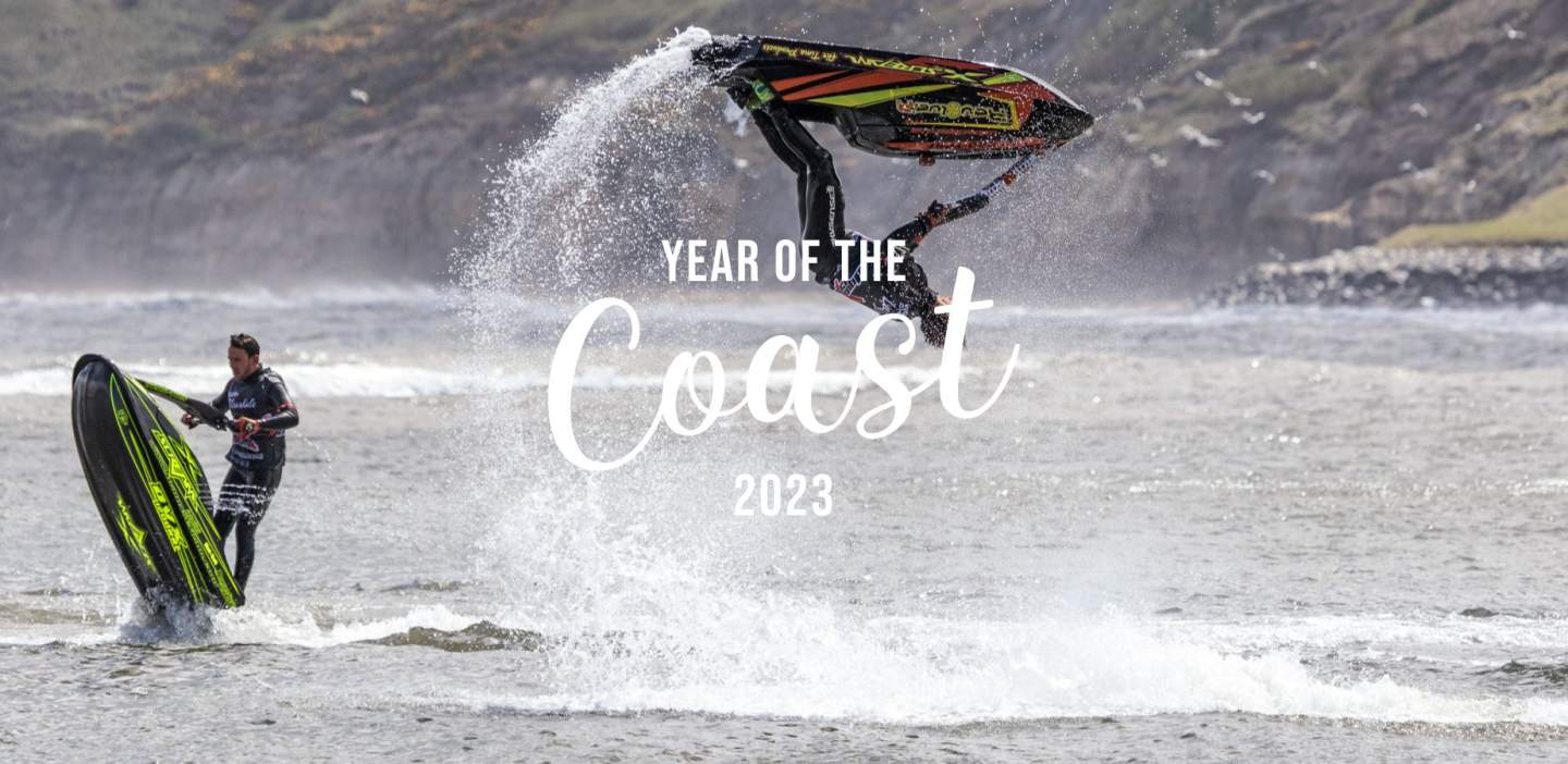 advert for "year of the coast" over an image of some jetskis doing sick flips