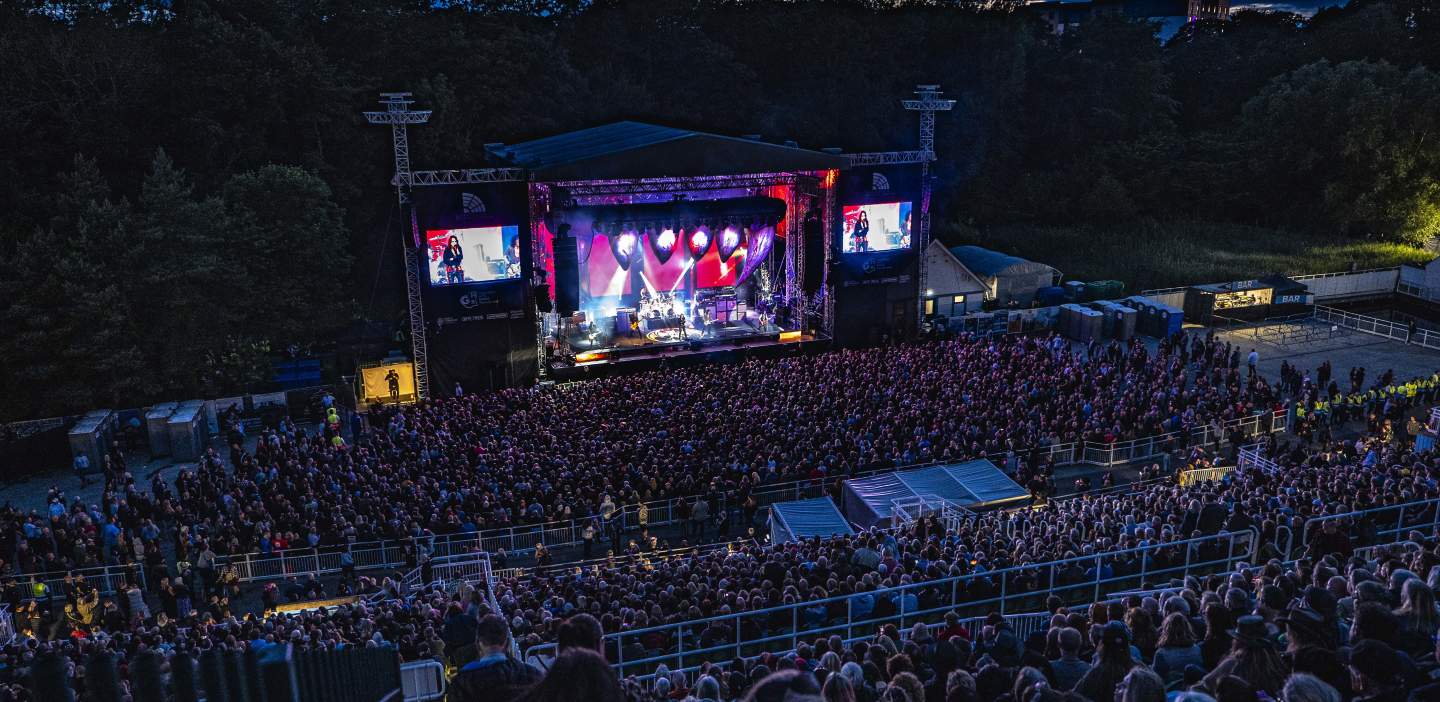Scarborough open air theatre at night, band in full swing, with thousands of people in the crowd