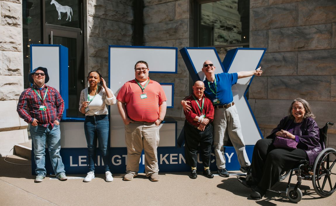 Men and women standing in front of LEX sign at the Lexington Visitors Center