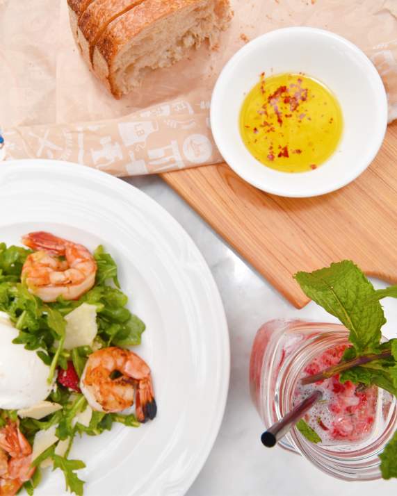 A plated shrimp salad and bread with drink at Louie Bossi in Fort Lauderdale, FL