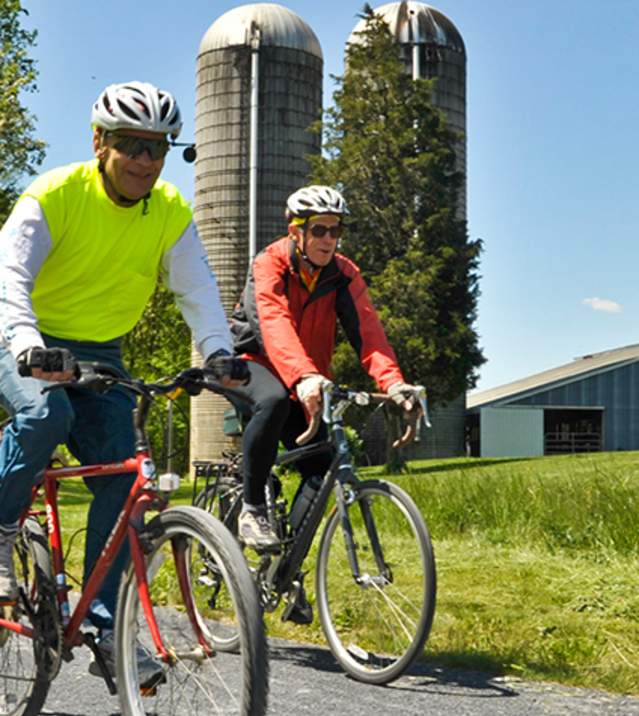 Friends ride their bikes along the Cumberland Valley Rail Trail on a clear spring day.