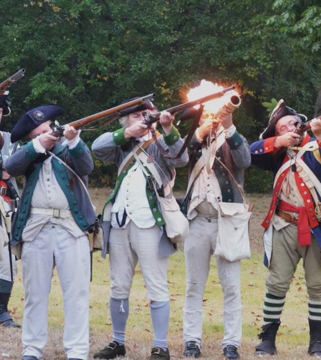 A group of historical Revolutionary War reenactors firing away at a Revolutionary War demonstration on Long Island.