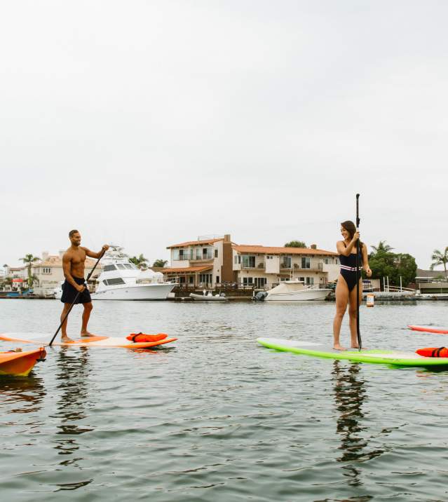 Kayaking in Huntington Harbour. Group of four people kayaking and Stand Up Paddleboarding