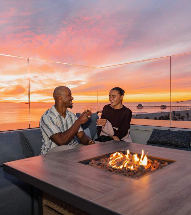 Couple cheerings at Offshore 9 Rooftop Lounge with the sunset in the background