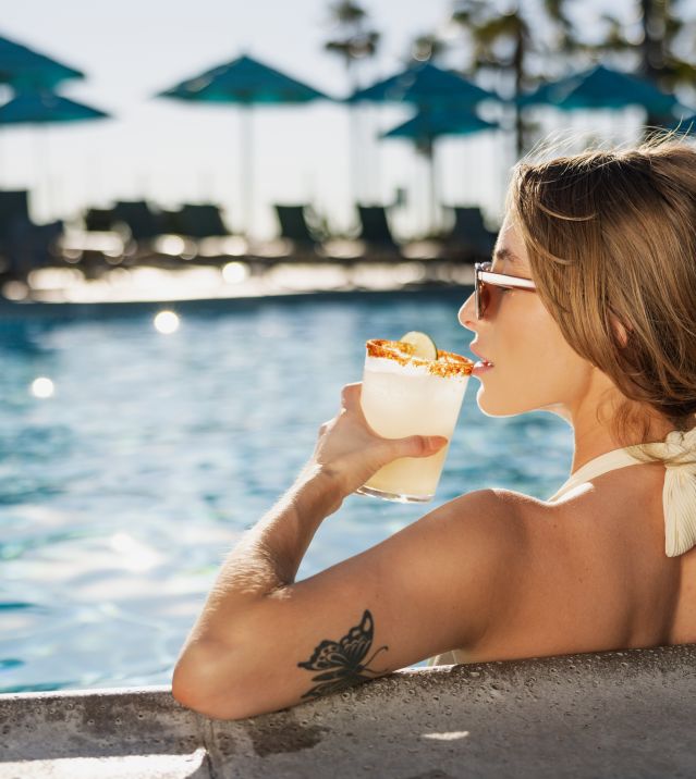 Woman sitting in swimming pool, enjoying a cocktail